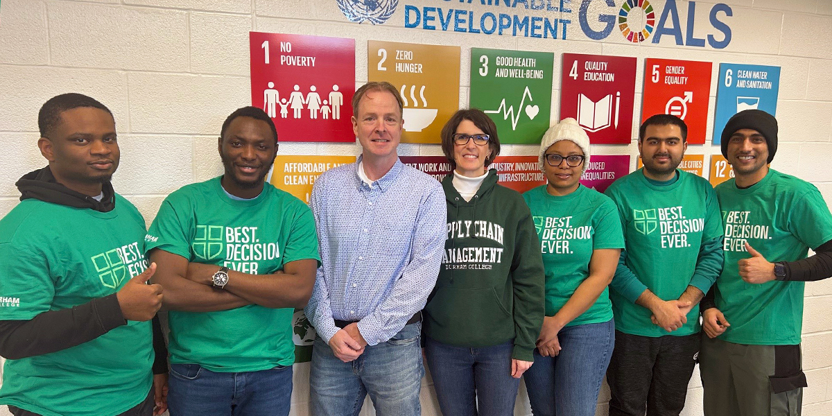 Students and Faculty members in green DC shirts and sweaters face the camera and smile.