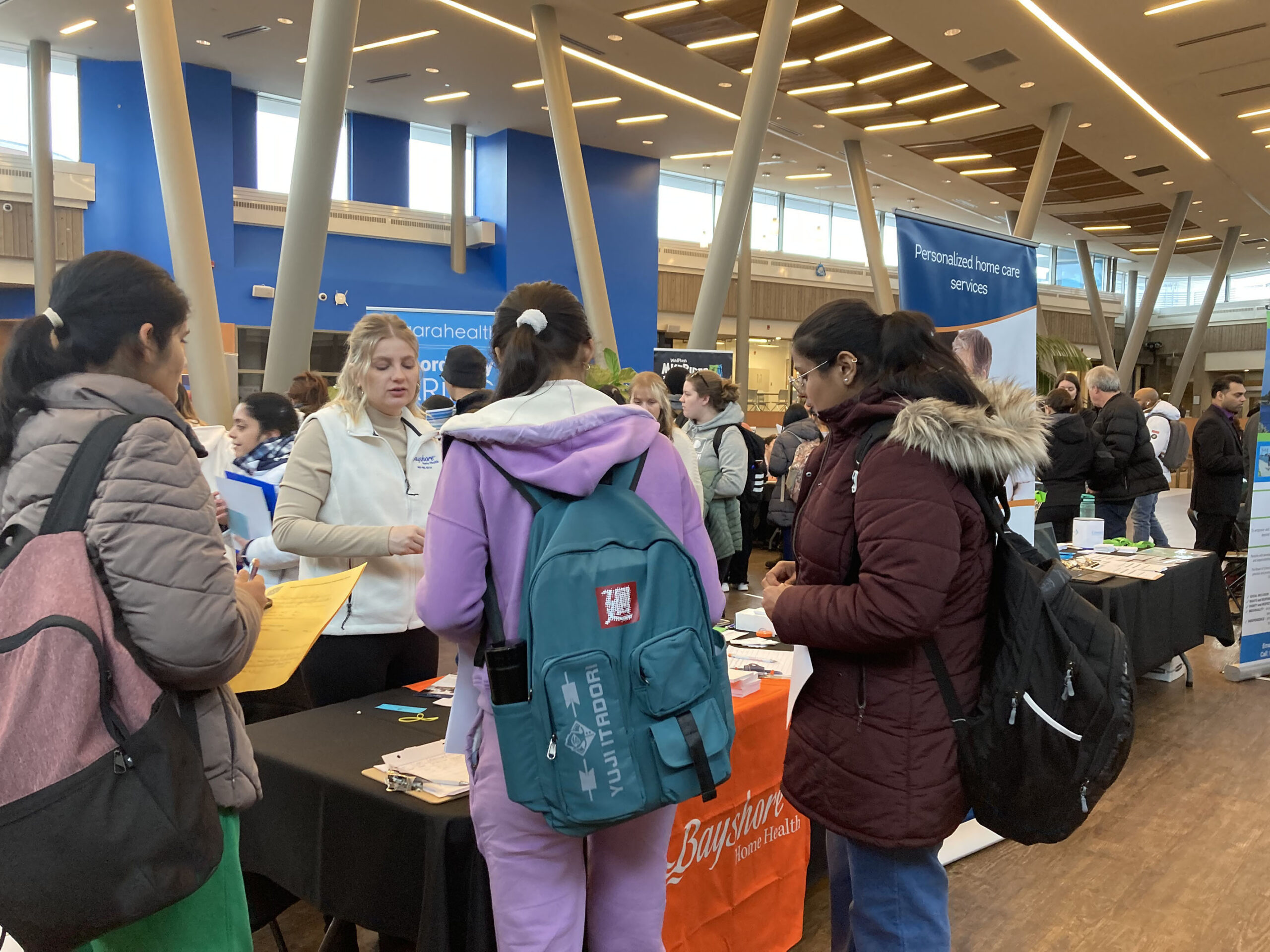 students attend a career fair and speak with an employer at a table