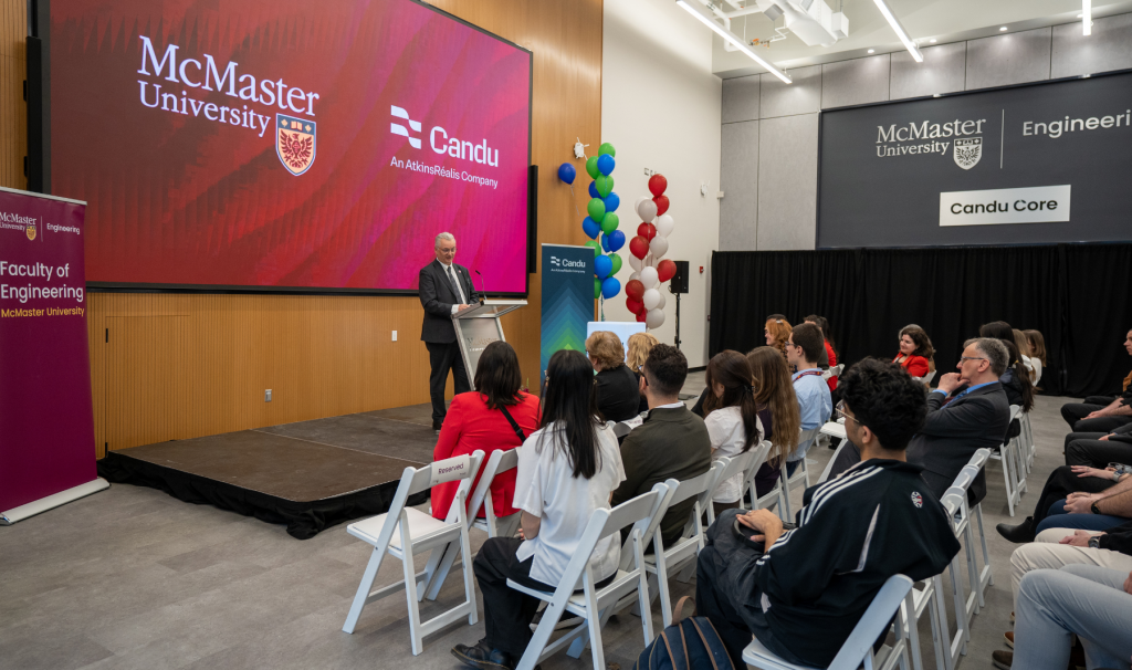 Audience members listen to a speaker at a podium in front of a McMaster Engineering and Candu backdrop.